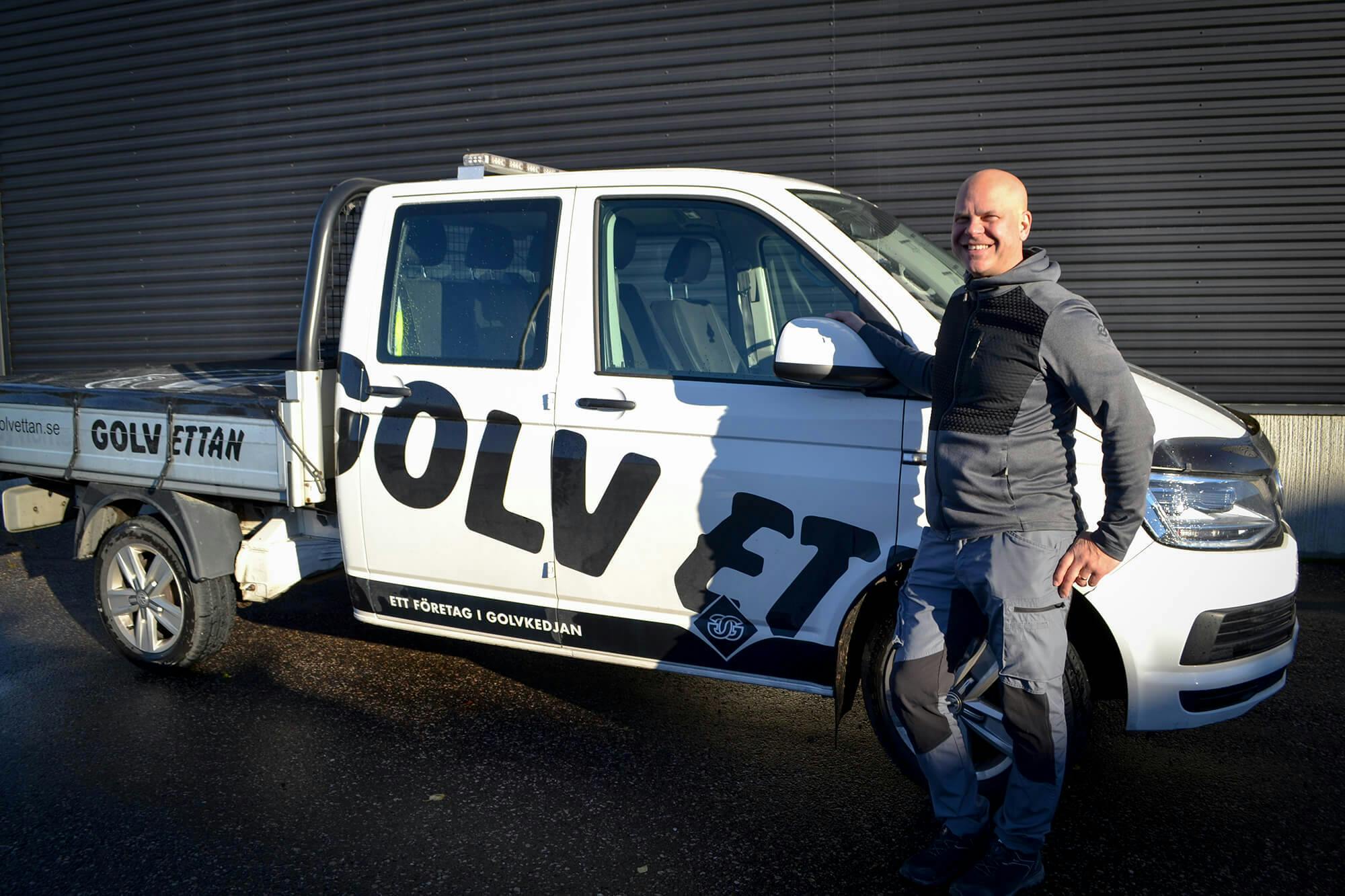Här står Johan Olsson bredvid företagets trotjänare, en Transporter pickup, som ständigt är i rörelse som Golv Ettans utkörningsbil.
